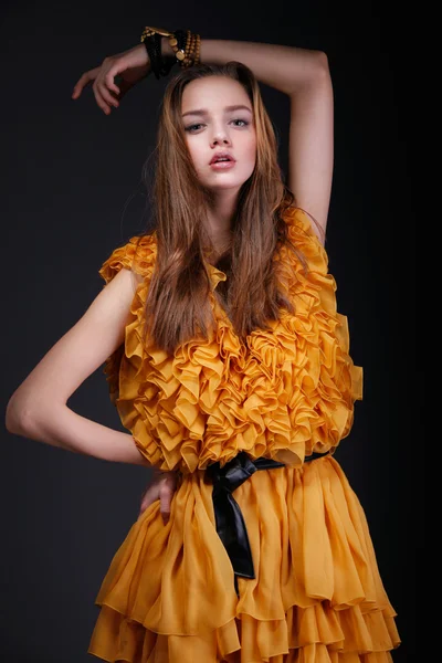 Attractive woman in yellow dress with hand above her head — Stock Photo, Image