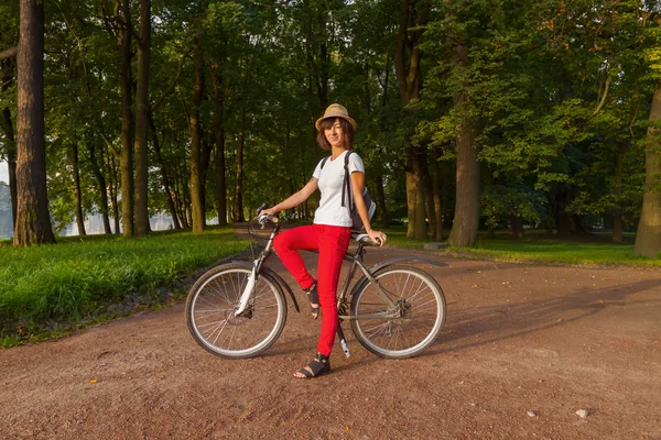 Hipster beautiful girl on a bicycle in the park — Stock Photo, Image