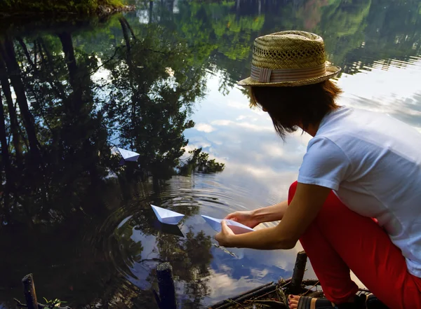 Девушка играет на бумажной лодке на реке — стоковое фото