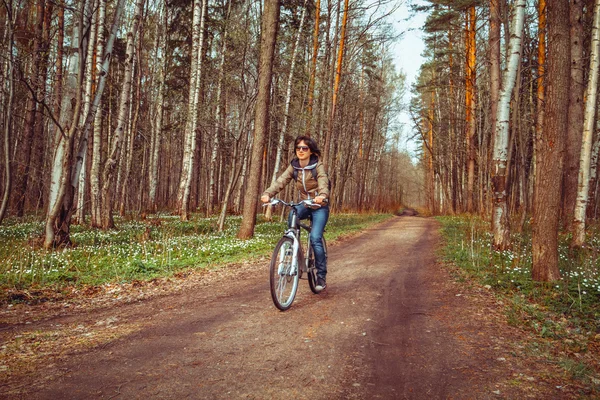 Mladá žena jedoucí na kole v lese — Stock fotografie