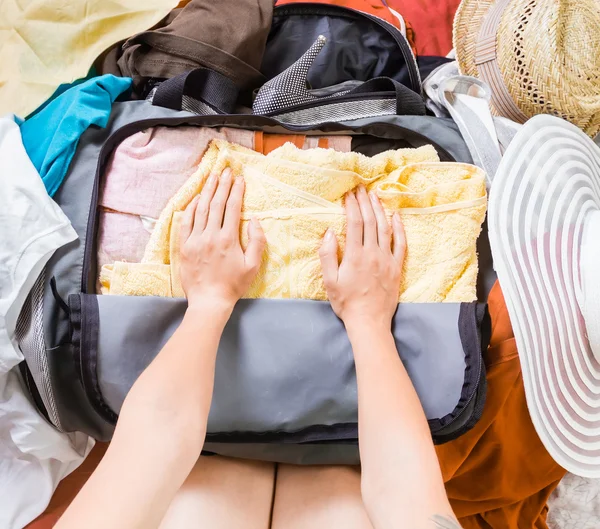 Mujer tratando de empacar ropa en una bolsa Fotos De Stock Sin Royalties Gratis