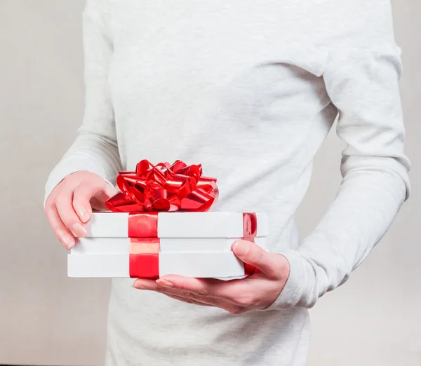 Gift with red ribbon in female hands — Stock Photo, Image