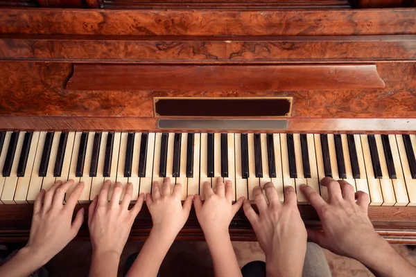 Familia de tres personas está tocando el piano, vista frontal — Foto de Stock