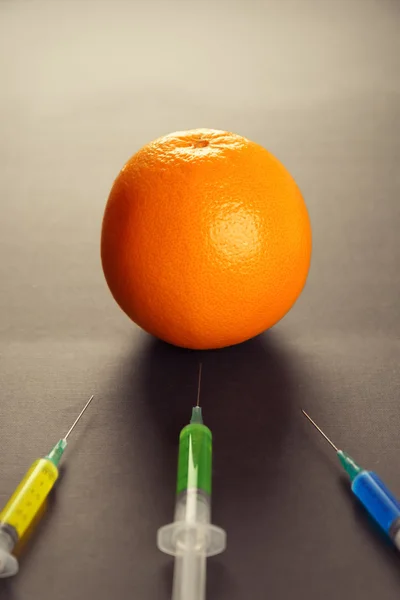 Orange and syringes with modification liquid — Stock Photo, Image