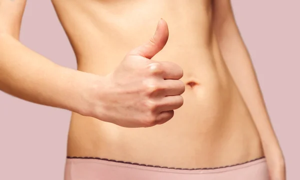 Woman with gesture thumb up in front of her belly — Stock Photo, Image