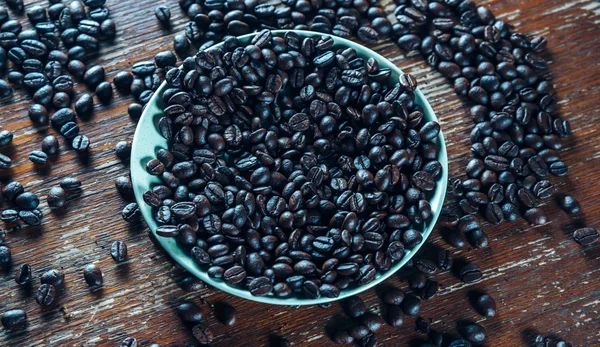Granos de café asados en un platillo —  Fotos de Stock
