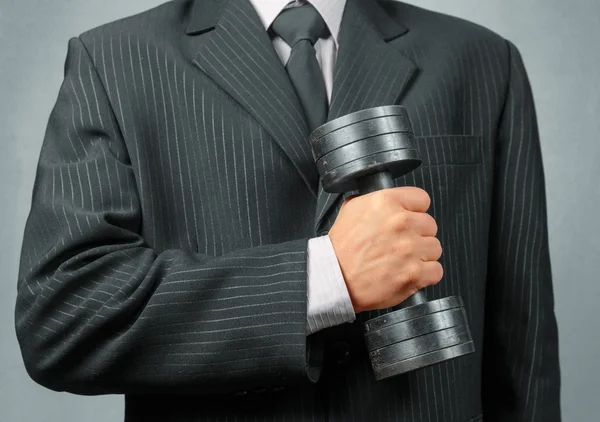 Businessman holds metal dumbbell — Stock Photo, Image