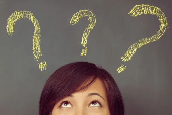 Woman looks at question marks — Stock Photo, Image