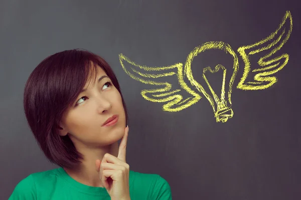 Woman thinks on the background flying light bulb — Stock Photo, Image