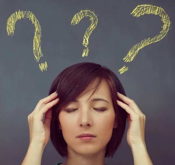 Soru işaretleri arka plan üzerinde baş ağrısı olan kadın — Stok fotoğraf