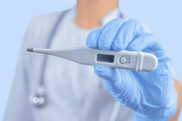 El médico sostiene el termómetro electrónico —  Fotos de Stock