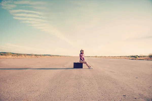 Hipster girl sits on suitcase — Stock Photo, Image