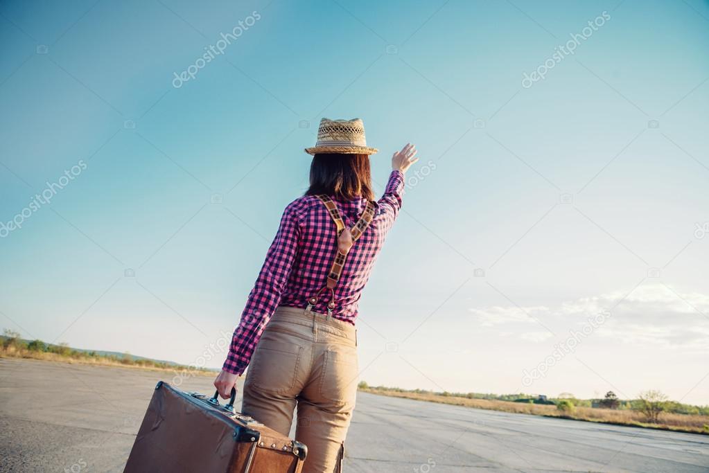 Woman with suitcase waves her hand away