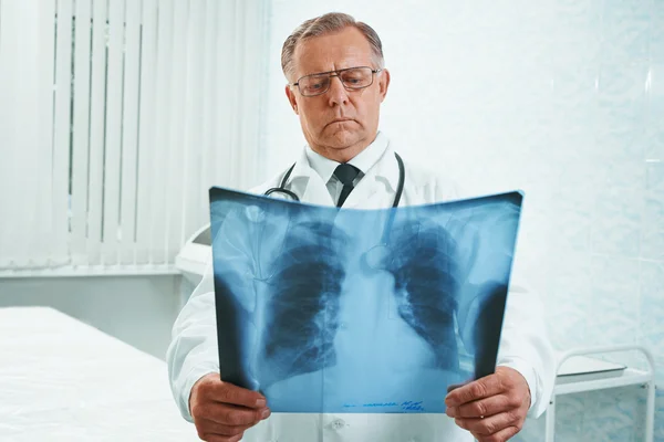 Un médecin plus âgé examine une image radiographique — Photo