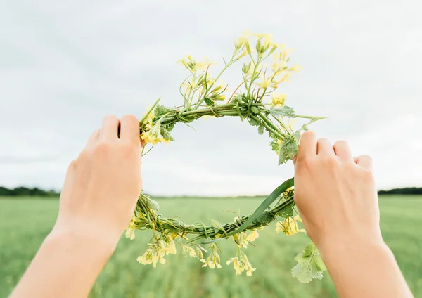 Mãos femininas com coroa de flores — Fotografia de Stock