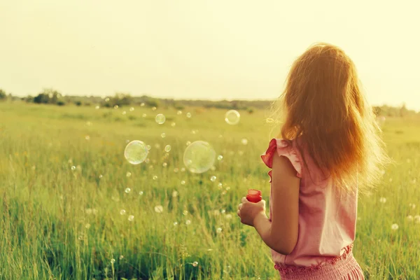 Girl is blowing soap bubbles — Stock Photo, Image