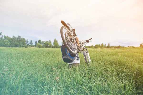 Radfahrer trägt Fahrrad im Feld — Stockfoto