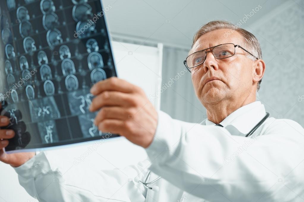 Older doctor examines MRI image