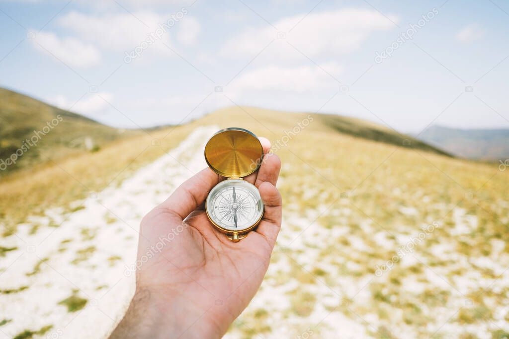 Travel concept. Vintage compass in hands in the mountains.