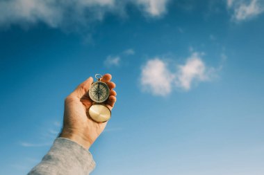 Mavi gökyüzüne karşı gezginlerin elinde klasik bir pusula.