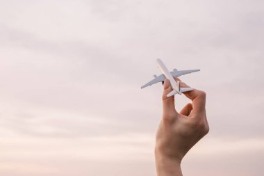 Arka planda bir kadın elinde uçak modeli.