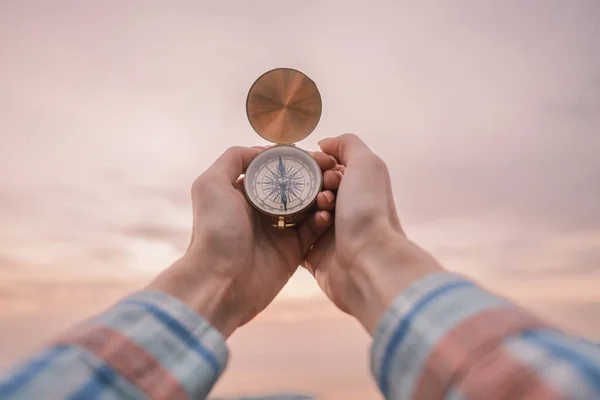 I kvinnliga händer en vintage kompass i bakgrunden av solnedgången himlen. — Stockfoto