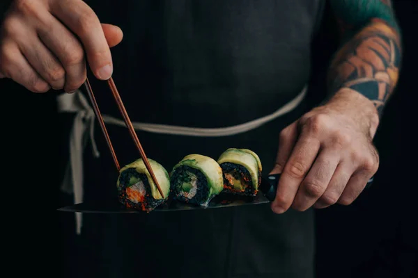 El chef toma un rollo con palos japoneses. — Foto de Stock
