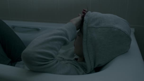 Joven mujer deprimida sentada en la bañera. — Vídeos de Stock