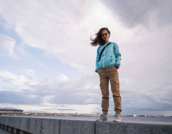 Giovane donna in posa sul terrapieno della città. Sullo sfondo il mare. Fotografia Stock