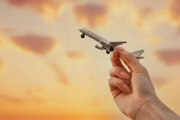 Modelo de avião em uma mão feminina no céu de fundo durante o pôr do sol. — Fotografia de Stock