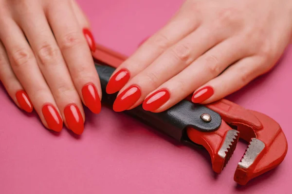 Detailní záběr ženské ruky s červenou manikúrou a instalatérským klíčem. — Stock fotografie