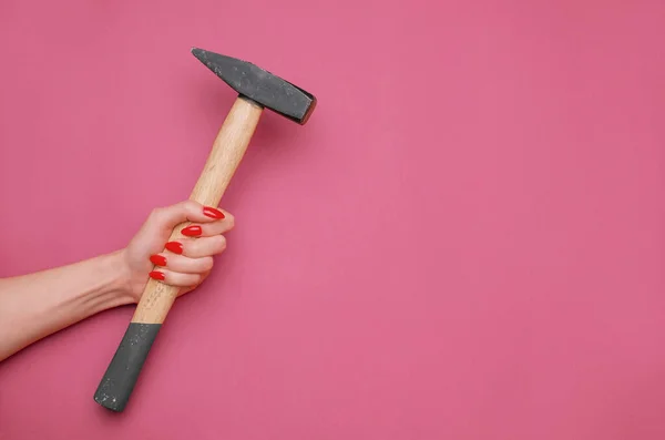 Mano femenina con manicura roja y martillo. — Foto de Stock