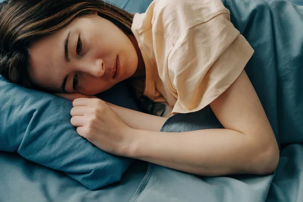 Uma jovem triste deita-se na cama e não consegue dormir. — Fotografia de Stock
