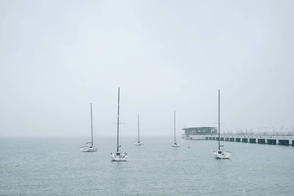 Verschillende zeiljachten liggen afgemeerd aan de pier in de zee. Rechtenvrije Stockfoto's