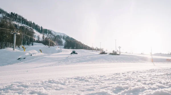 Declive de esqui Rosa Khutor com snowcats durante a preparação de pistas para esquiadores e snowboarders. — Fotografia de Stock