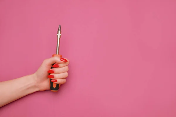 Mano femminile con una manicure rossa e un cacciavite. — Foto Stock