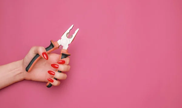 Vrouwelijke hand met rode manicure en tang. — Stockfoto