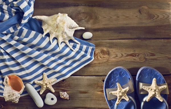 Strand flip-flops, gestreepte jurk, schelpen op een houten vloer. — Stockfoto