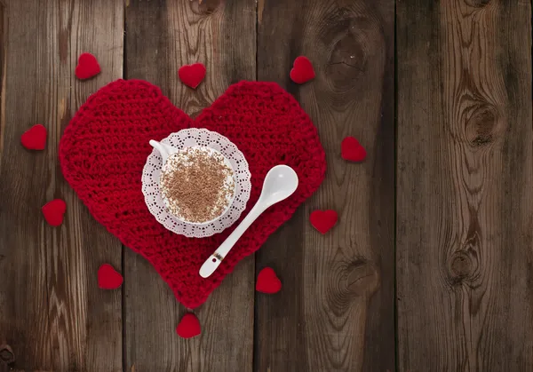 Taza de café con crema batida en un corazón de punto rojo . — Foto de Stock