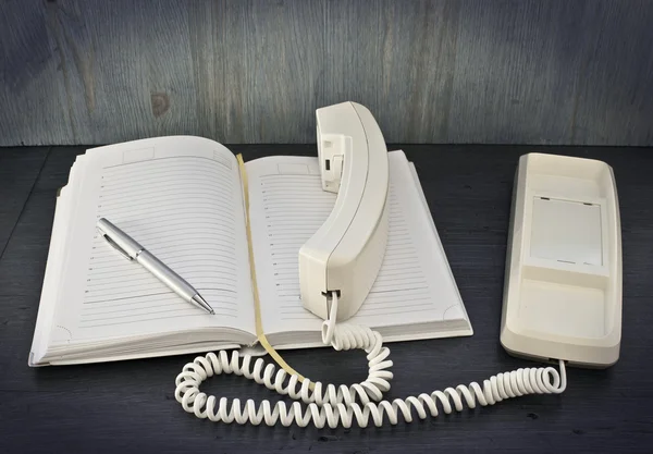 Telefoon, pen, notitieblok op houten tafel — Stockfoto