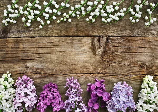 Lilies of the valley and lilac colored wooden texture. Unusual f — Stock Photo, Image