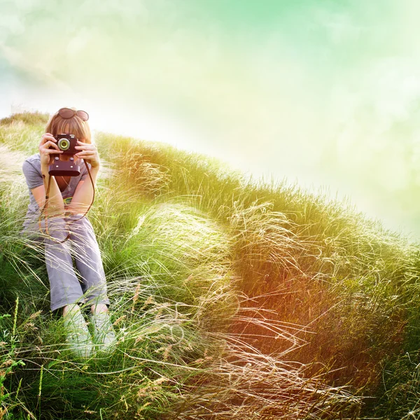 Girl sitting on the grass with a retro camera — Stock Photo, Image