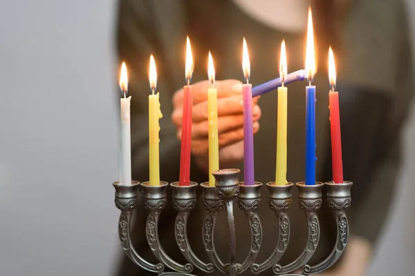 Joodse vrouw die Chanoeka Kaarsen aansteekt in een menorah. — Stockfoto