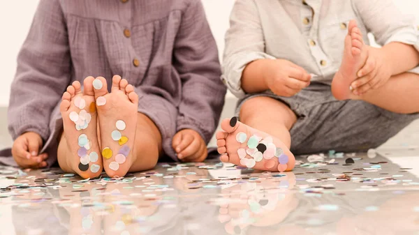Маленькі дитячі ноги покриті різнокольоровими конфетті . — стокове фото