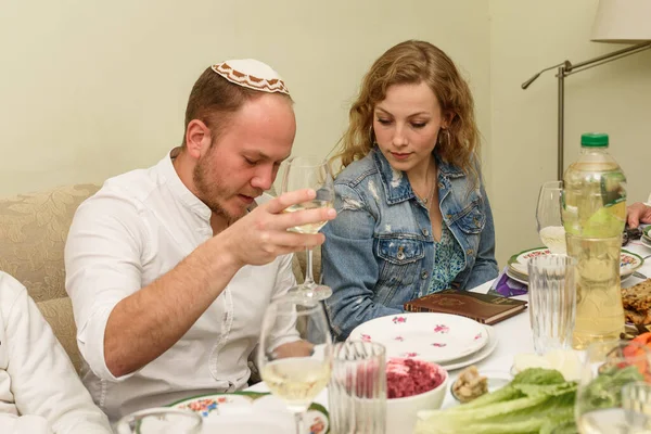 Jewish family at the table with traditional food celebrating Passover Seder.