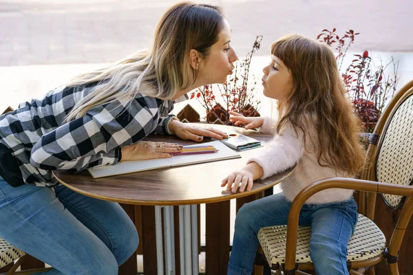 Mother kissed her little daughter while having a family breakfast outdoors. — Stock Photo, Image