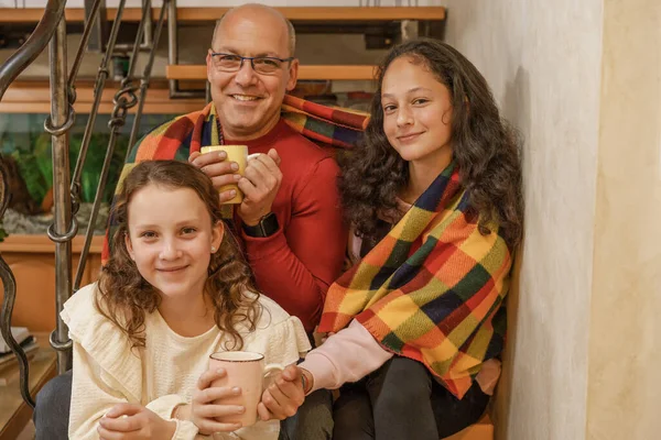 Glückliche Familie - Vater und junge Mädchen reden und lachen, wenn sie zu Hause in eine Decke gehüllt sitzen. — Stockfoto