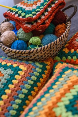 Örgü projesi. Saman sepetinde renkli yün iplikler ve kanepede örgü yastıklar. Sepete seçici odaklanma.