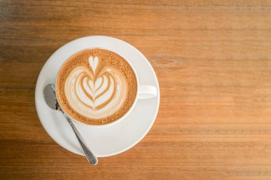 Sütlü sütlü sütlü sütlü sıcak kahve fincanı ahşap masanın üstünde. İş konsepti sırasında bir kafede kahvaltı olarak.