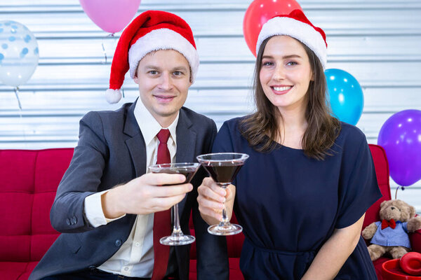Happy new year 2022 concept,Happy couple of wrist in a business suit holding glasses of Clinking Champagne in Christmas and New Year's Eve party After finishing business work